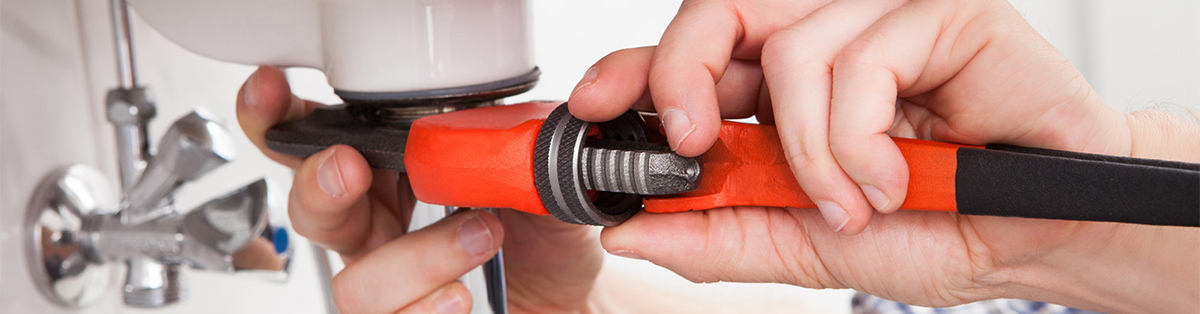 Young plumber fixing a sink in bathroom